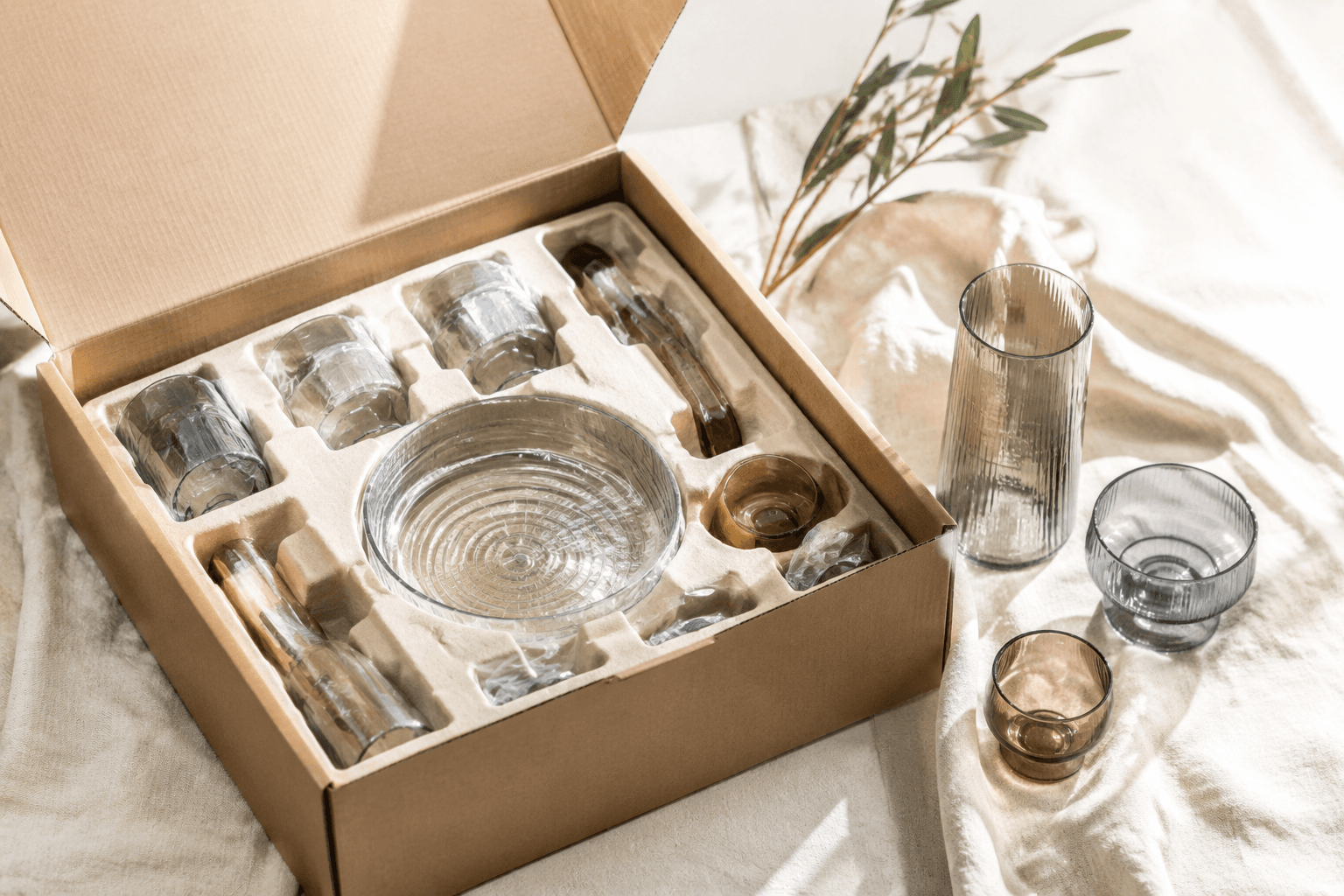 An open shipping box with molded inserts protecting wrapped glass homeware